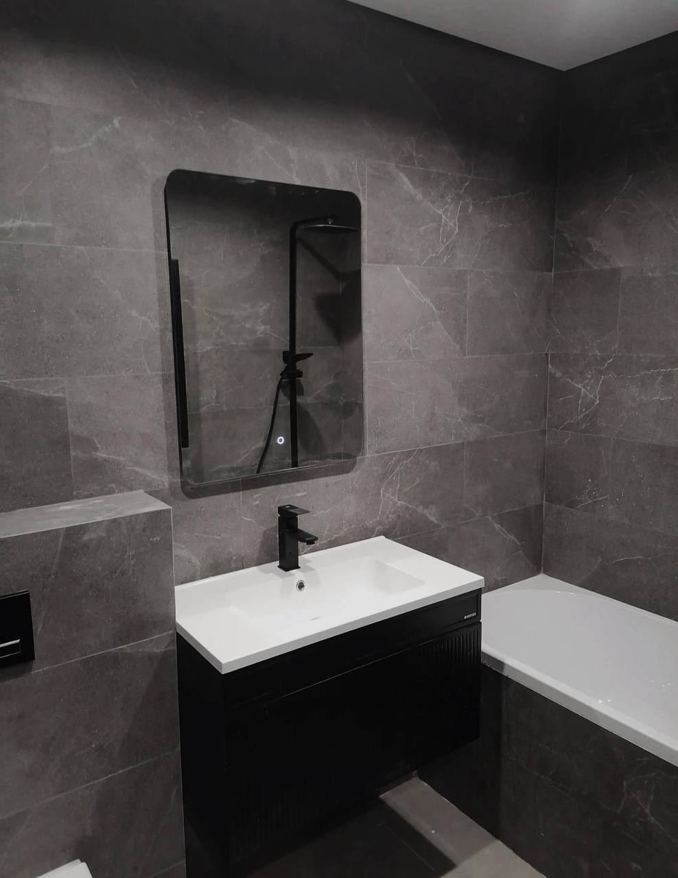 Donkere badkamer met zwart meubel en ligbad
